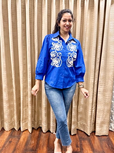 A striking royal blue shirt Decorated with white floral applique embroidery on the front